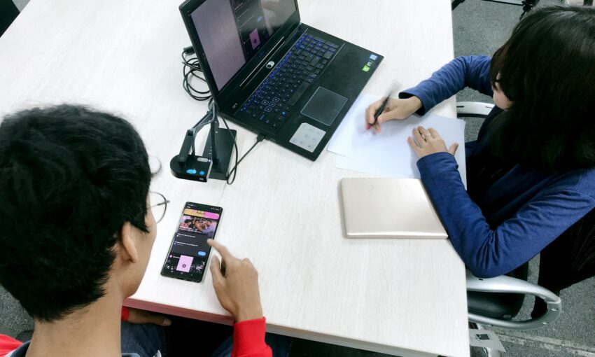 UX testing with two people, one taking notes and one reading a screen and scrolling.
